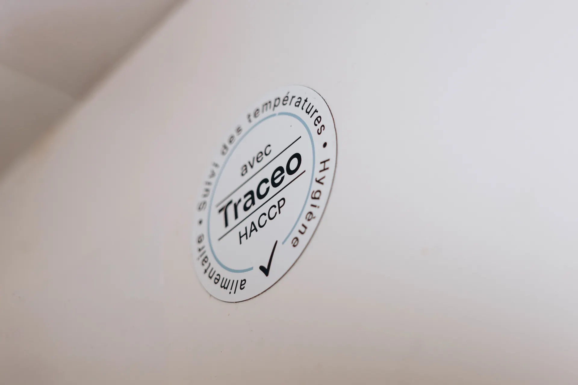 Pastille « avec Traceo HACCP, suivi des températures, hygiène alimentaire » collée sur la paroi blanche d’une chambre froide
